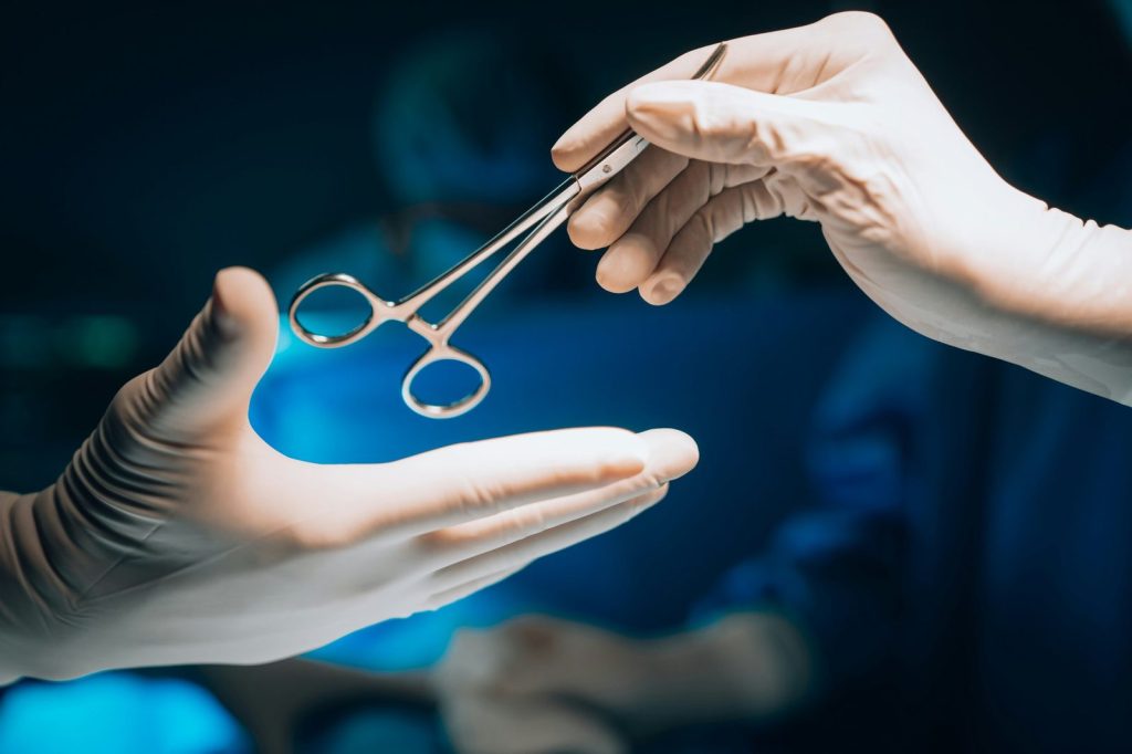 Accueil Passage d'un instrument chirurgical entre deux mains gantées au bloc opératoire