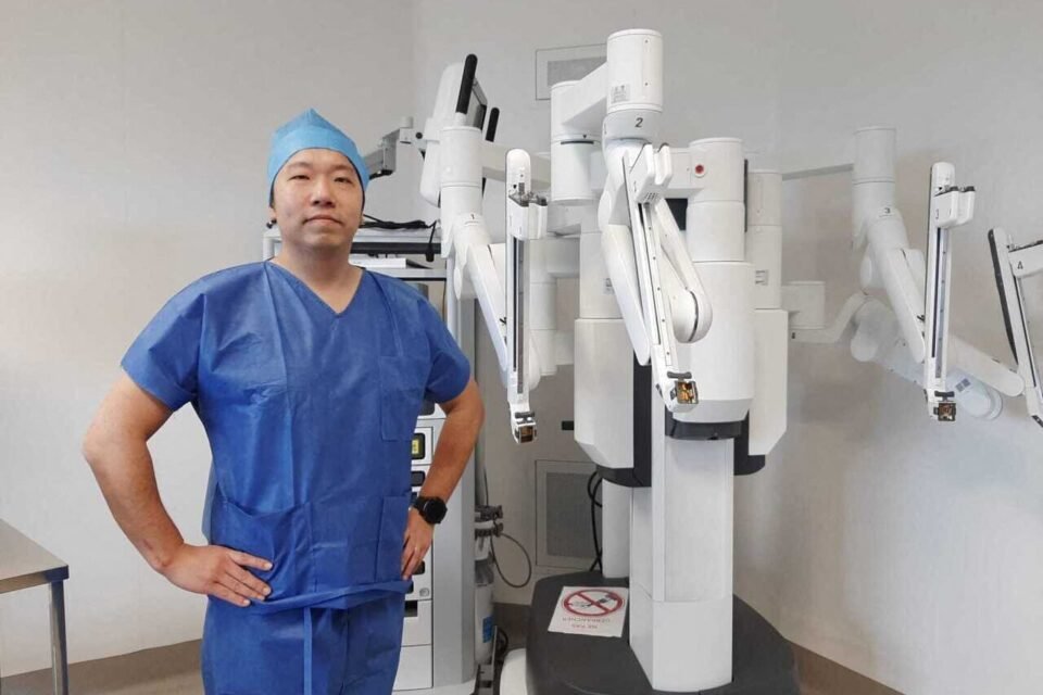 Le Dr Haixia Ye, chirurgien urologue, à côté du robot chirurgical Da Vinci X de la clinique
