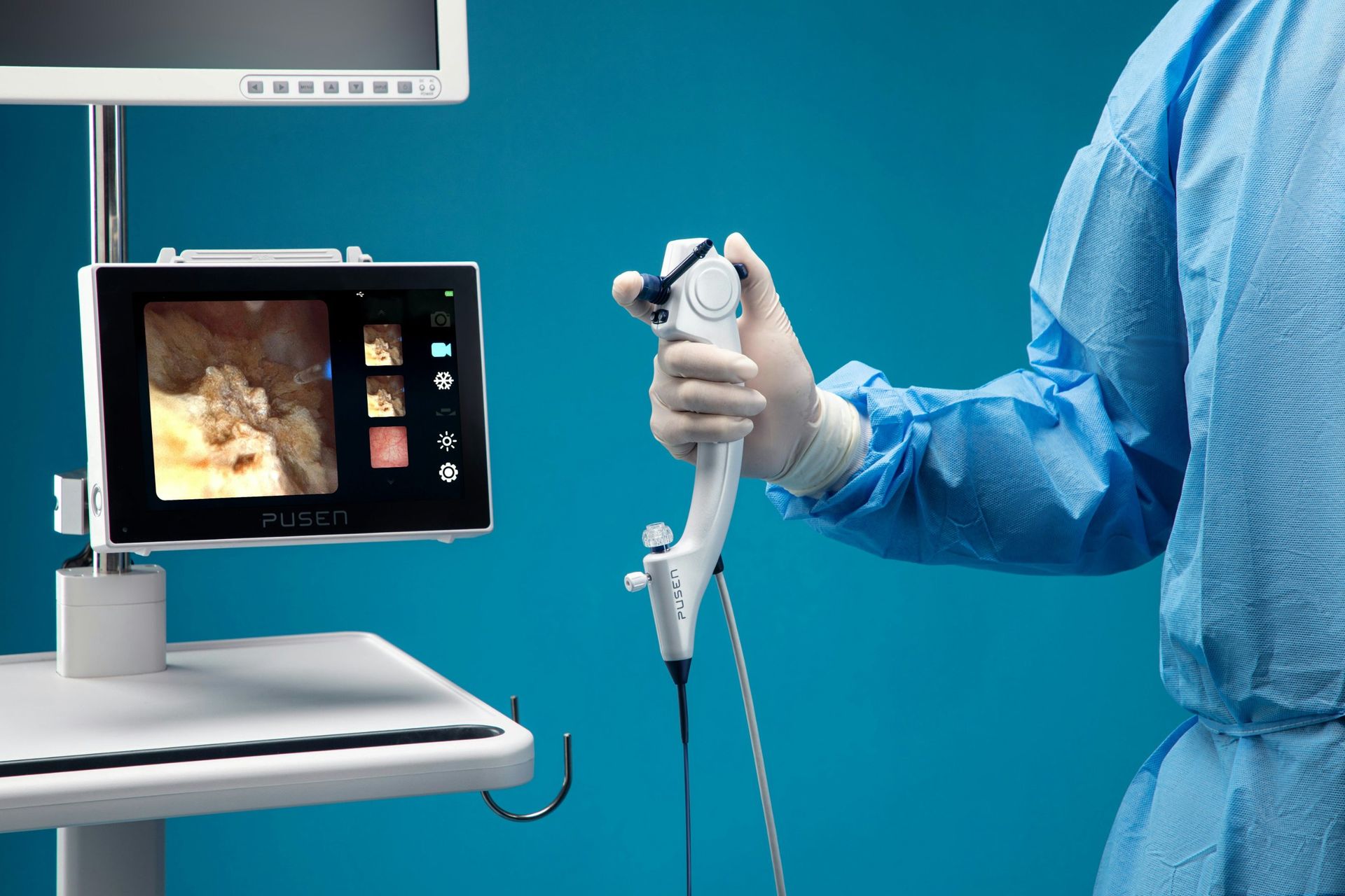 Endoscope souple tenu par une main gantée, à côté de l'écran de visualisation