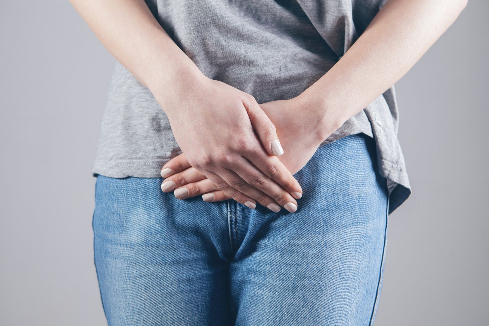Femme les mains croisées devant le bas-ventre