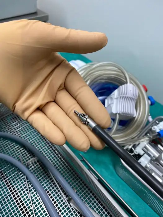 Extrémité d'un instrument articulé du robot chirurgical, posée sur une main gantée